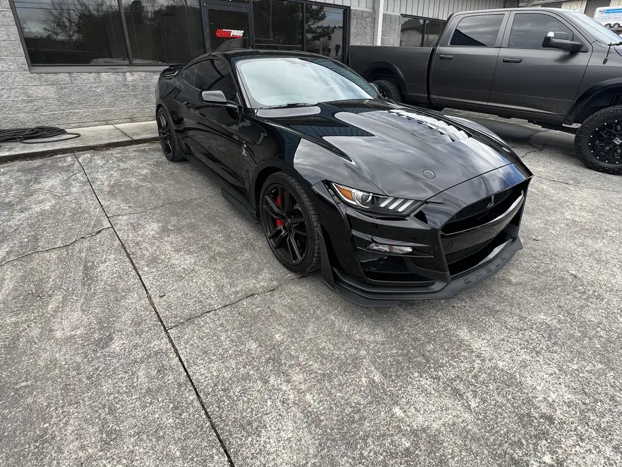 A black Shelby Mustang parked outside the shop after its repair