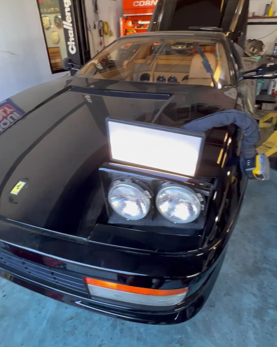 A black sports car with the hood open at the shop