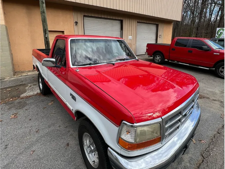 A red and white Ford pickup, freshly painted, outside the shop