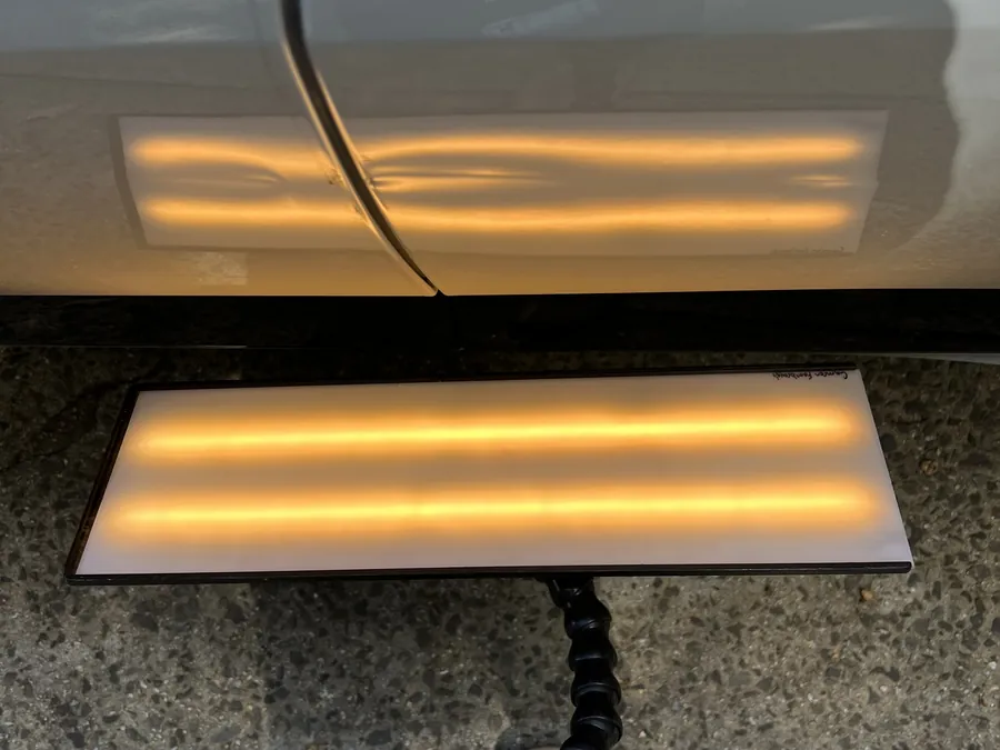 The LED dent board laid flat on a panel to read a dent